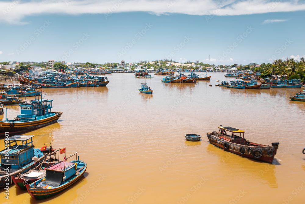 Traditional Vietnamese boats by yellow brown water in canal. 