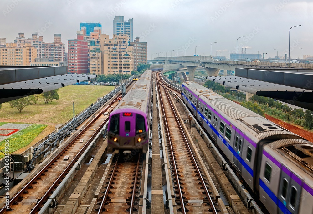Naklejka premium Scenic view of a metro train traveling on elevated rails of Taoyuan Mass Rapid Transit System (Taoyuan International Airport MRT System) under cloudy sky in Linkou, New Taipei City, Taiwan
