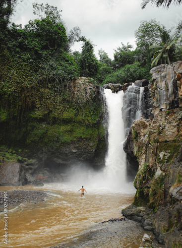 A man is bathing in a waterfall
