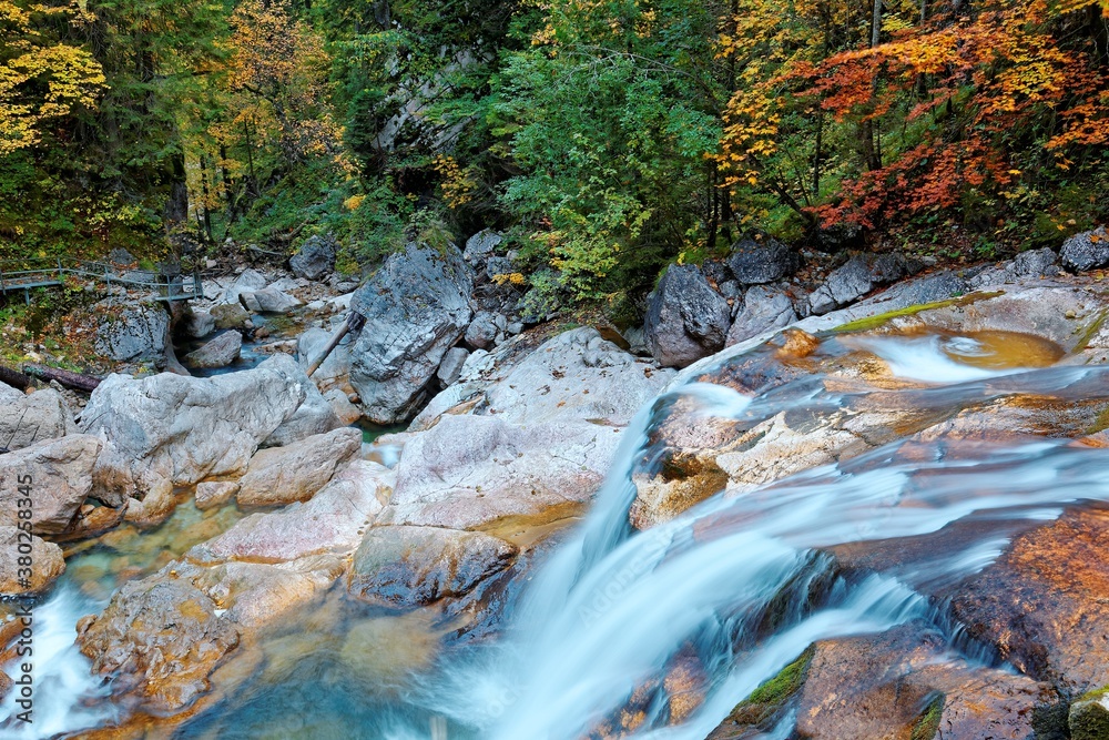 Scenic view of a waterfall tumbling down the rocks into a rapid stream ~ Scenery of a stream and cascades in an autumn valley near Neuschwanstein in Bavaria, Germany Scenic view of a waterfall tumbling down the rocks into a rapid stream ~ Scenery of a stream and cascades in an autumn valley near Neuschwanstein in Bavaria, Germany