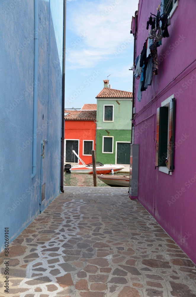 Burano island near Venice in Italy, view through colorful houses towards a canal, copy space