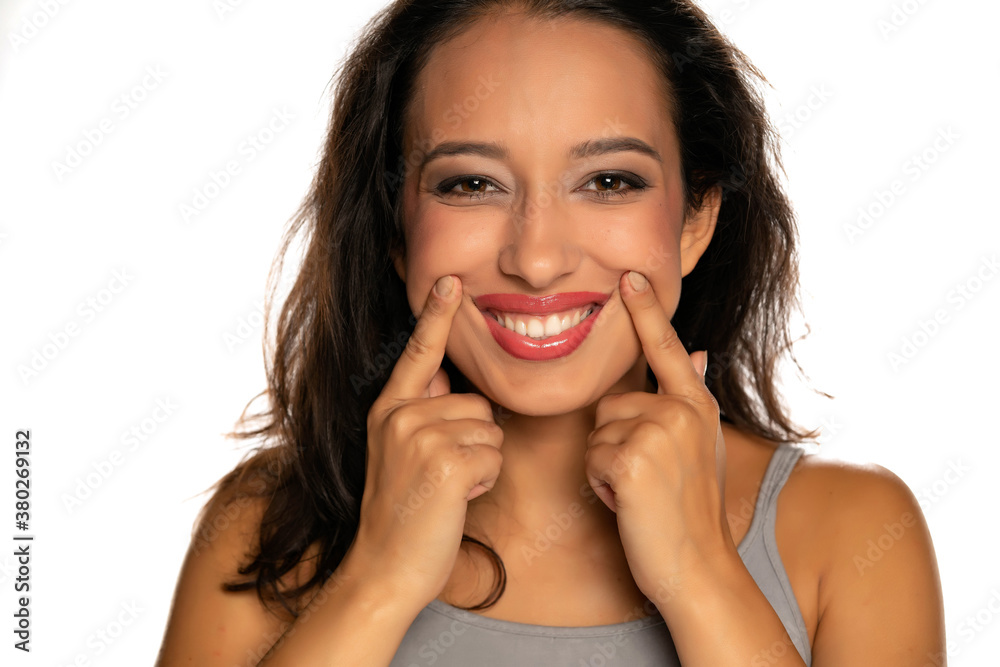 Young dark skinned woman forcing her smile with her fingers Young dark skinned woman forcing her smile with her fingers