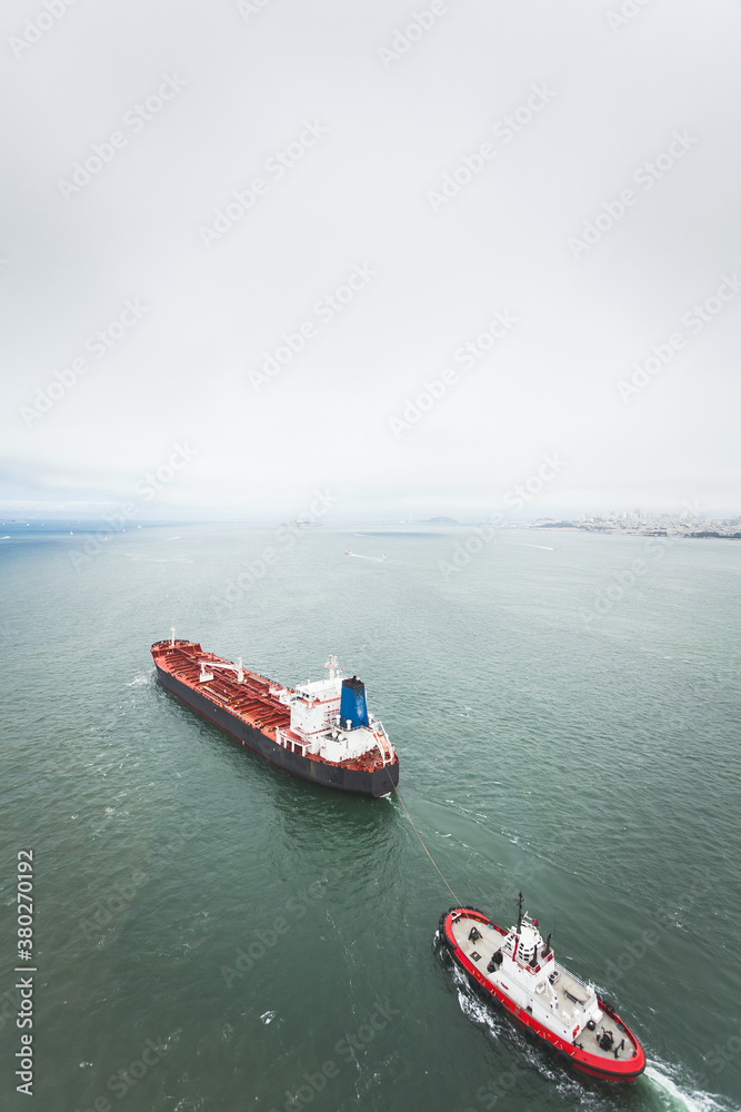 A large freighter pulls a tug boat under the Golden Gate Bridge in San Francisco. A large freighter pulls a tug boat under the Golden Gate Bridge in San Francisco.