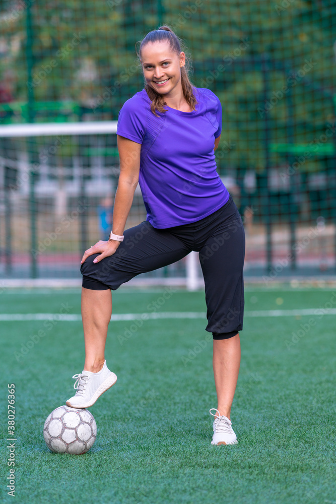 Smiling fit woman posing with a soccer ball