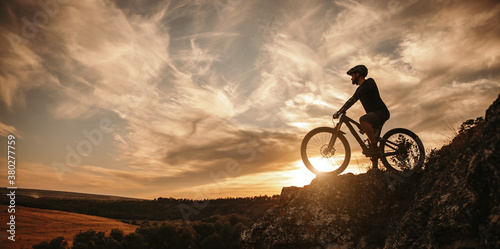 Man on mountain bike against sundown sky