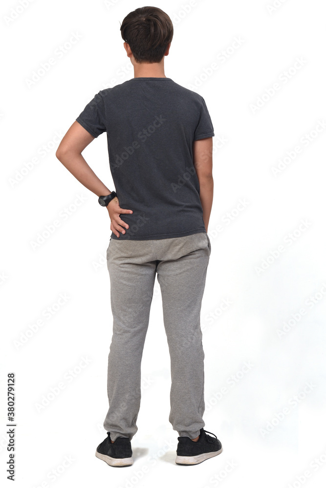 Fototapeta premium full portrait of a teenage boy dressed in sportswear on white background, back view and hand on hip