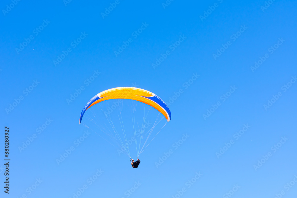 Paraglider in the blue sky. The sportsman flying on a paraglider. Paraglider in the blue sky. The sportsman flying on a paraglider.