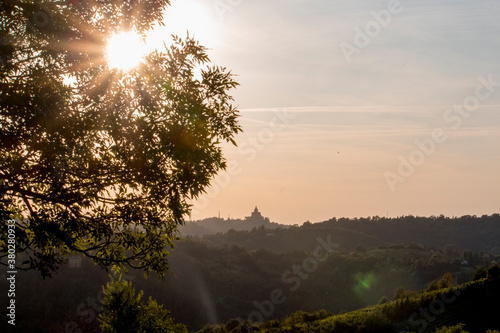 Panoramic view of San Luca Sanctuary at the sunset, with orange sky and sun in the background. There is the wood of the Bologna's hills ( colli bolognesi). Emilia Romagna Region.