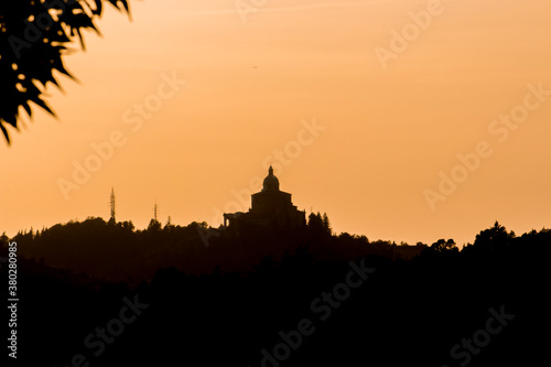 Panoramic view of San Luca Sanctuary at the sunset  with orange sky and sun in the background. There is the wood of the Bologna s hills   colli bolognesi . Emilia Romagna Region.