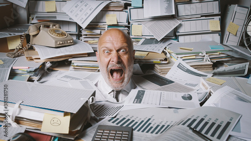 Stressed businessman buried under a lot of paperwork photo