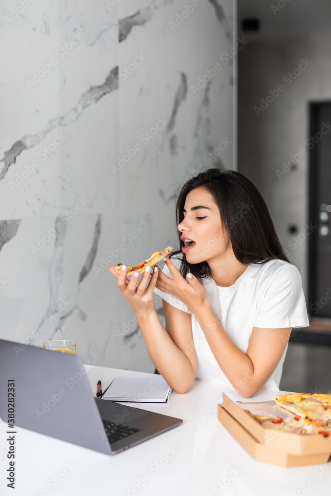 Young woman eating pizza and looking at laptop. Working from home Young woman eating pizza and looking at laptop. Working from home
