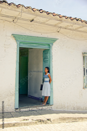 Young attractive latin woman waiting at the entrance of colonial house