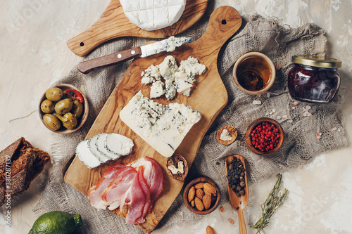 Set of cheese, hamon, honey, green olives, nuts and spices on rustic wooden board