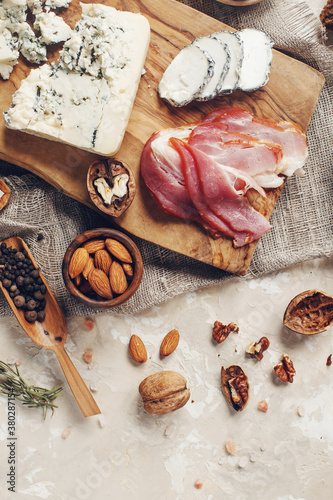 Set of cheese, hamon, honey, green olives, nuts and spices on rustic wooden board