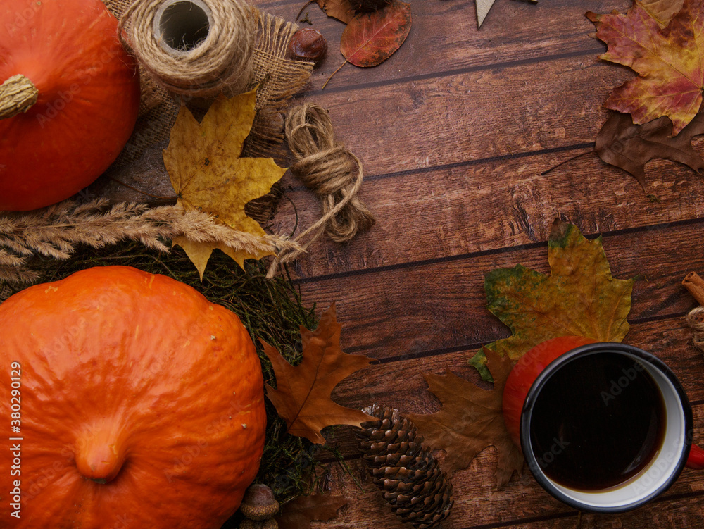 there is a mug with coffee and orange pumpkins on the table. selective focus