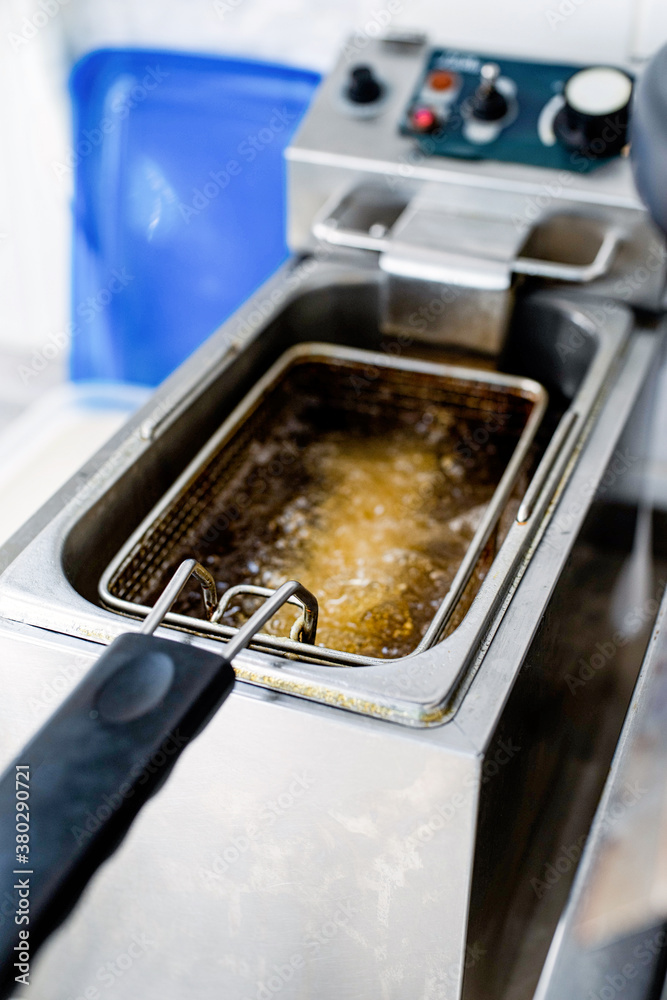Close up view of making french fries deep frying in an equipment in fast food court Close up view of making french fries deep frying in an equipment in fast food court