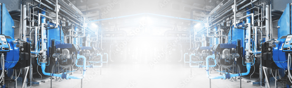 Modern industrial gas boiler room equiped for heating process. Heating boilers located symmetrically in two rows, pipes,pipelines, valves. Panoramic banner with copy space in middle. Blue toning.