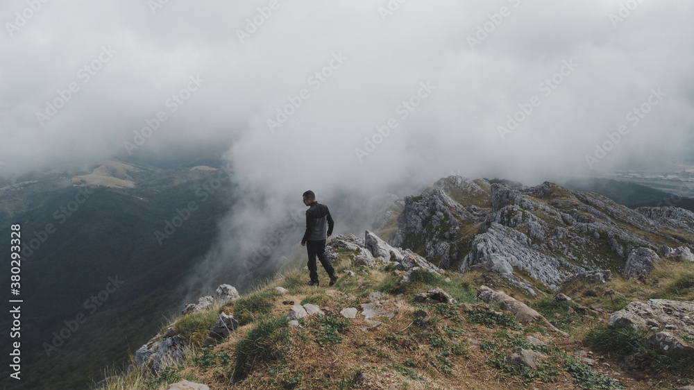 Senderista de espaldas en la cima de una montaña en el Parque Natural Aizkorri-Aratz en Guipúzcoa un día de nubes bajas