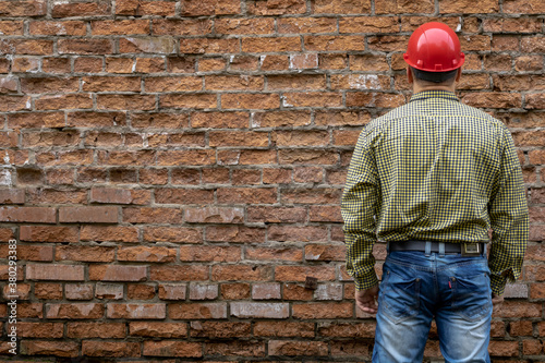 Builder in a hard hat on a brick wall background.