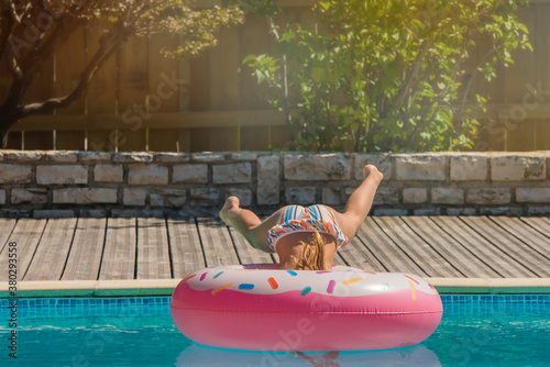 cute young girl playing in the pool with her inflatable donut © Image'in