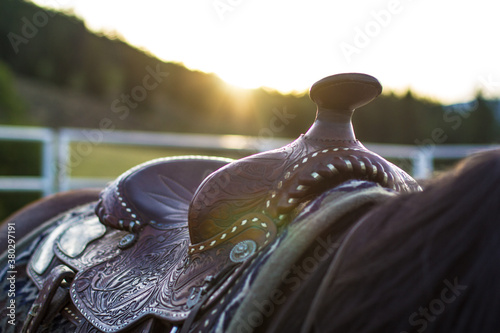 Close-up of a horse saddle with the setting sun in the background photo