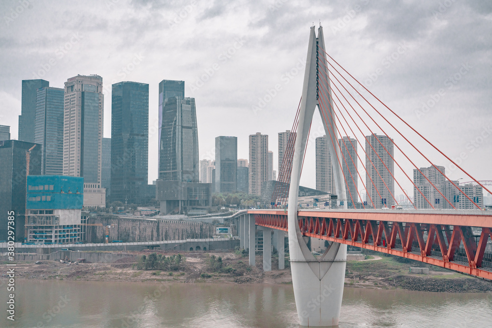 Obraz premium Panorama view of the Qiansimen bridge and skyline in Chongqing, China, on a cloudy day.