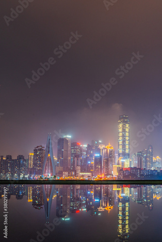 Night view of the skyline of downtown Chongqing on a cloudy day  with reflection in front.