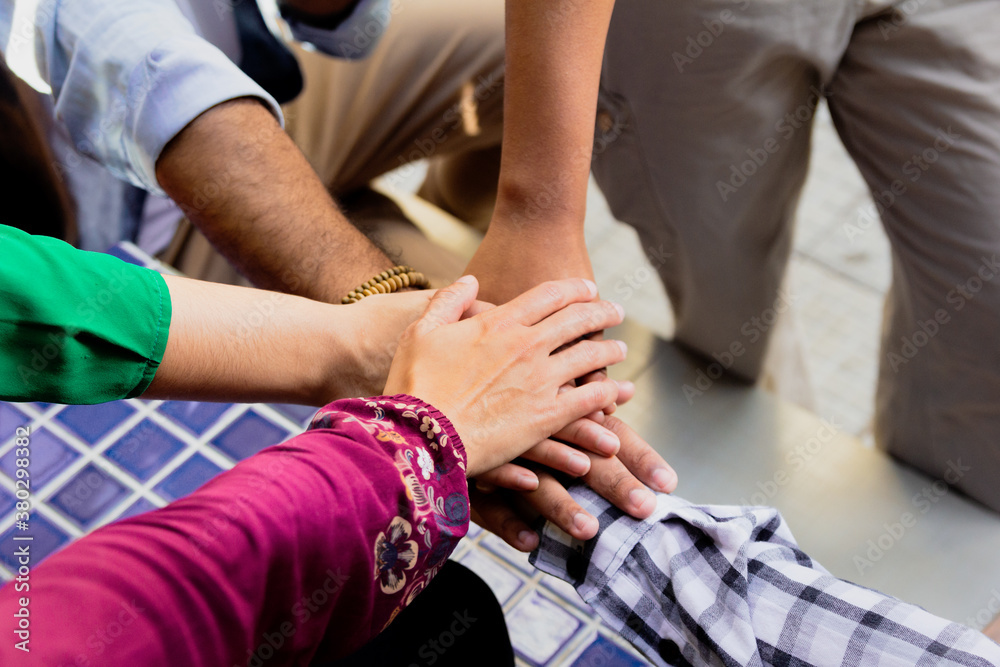Hands joined, one over the other. All together in a team. Teamwork and unity. Men and women come together to cooperate and work. Hands joined, one over the other. All together in a team. Teamwork and unity. Men and women come together to cooperate and work.
