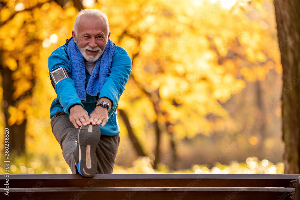 Senior man stretching outdoors. - obrazy, fototapety, plakaty 