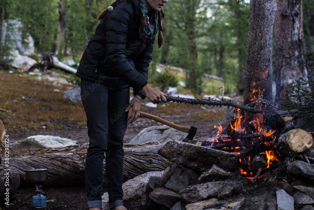 Woman throws a piece of wood onto a campfire Woman throws a piece of wood onto a campfire