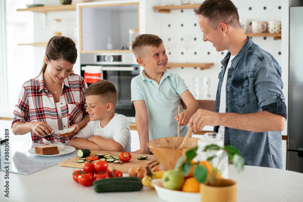 Mother and father making breakfast with sons. Young family preparing delicious food in kitchen Mother and father making breakfast with sons. Young family preparing delicious food in kitchen