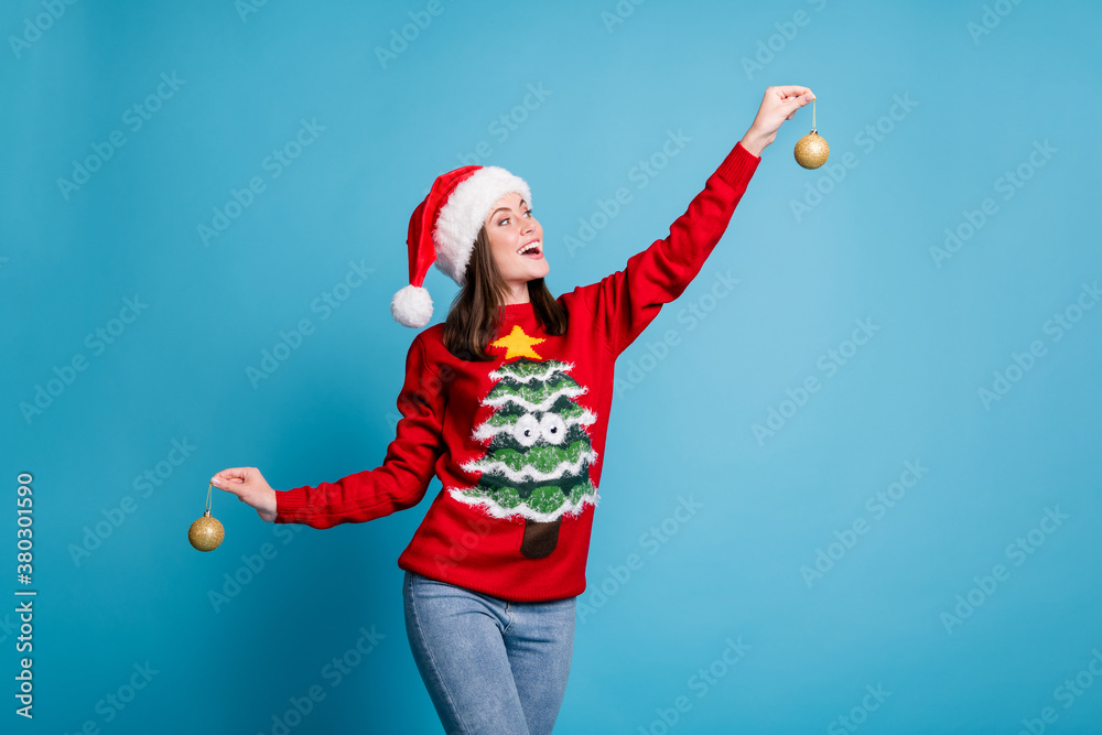 Obraz premium Photo portrait of woman holding two christmas shiny golden baubles isolated on pastel light blue colored background