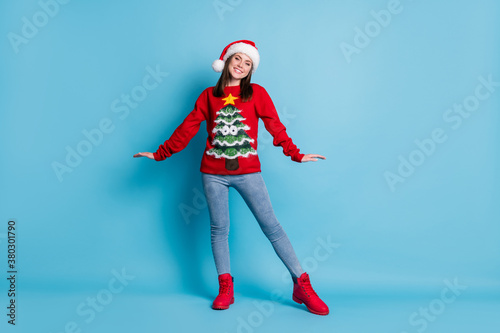 Full body size photo of adorable charming lady girlish posing shiny smiling wear santa x-mas headwear red ornamented pullover jeans boots isolated blue color background