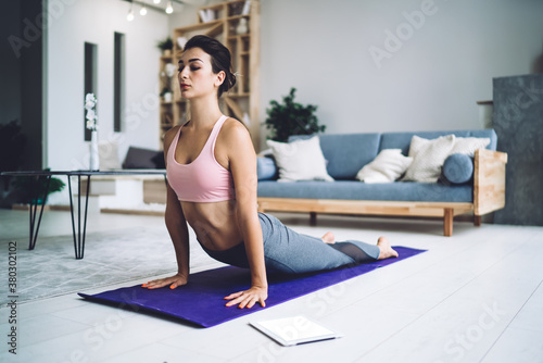 Sporty woman stretching back on mat while practicing yoga