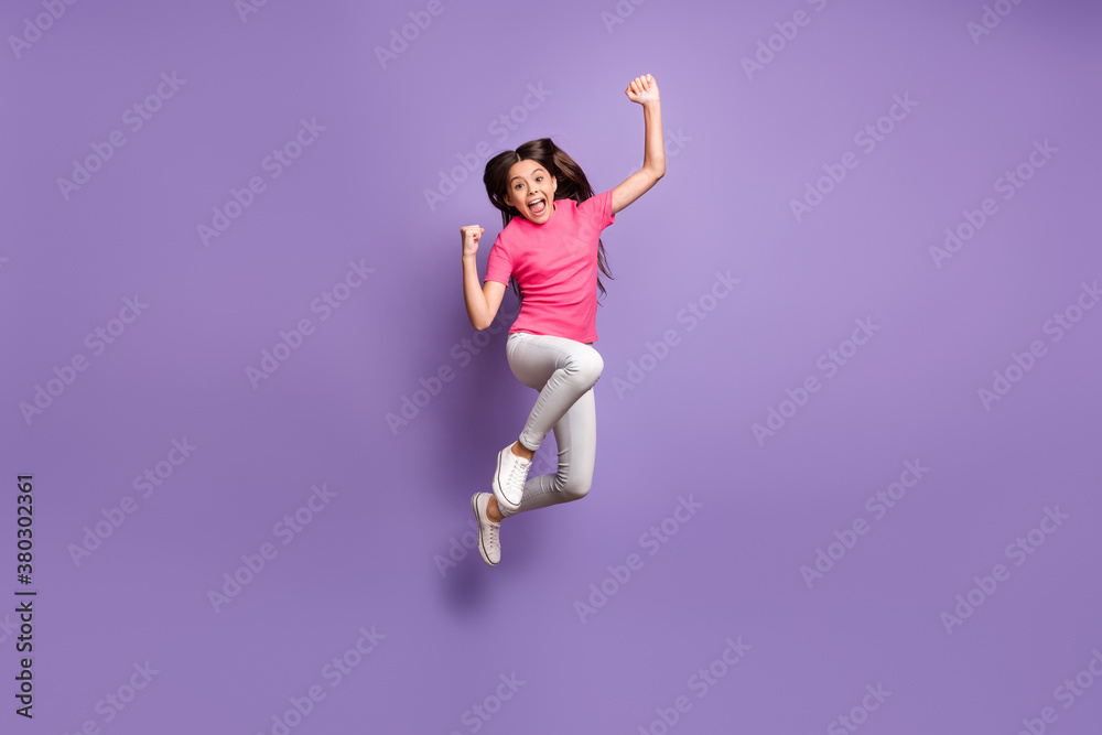 Full length body size photo of jumping high cute little female fan celebrating win cheering shouting loudly smiling isolated on purple color background