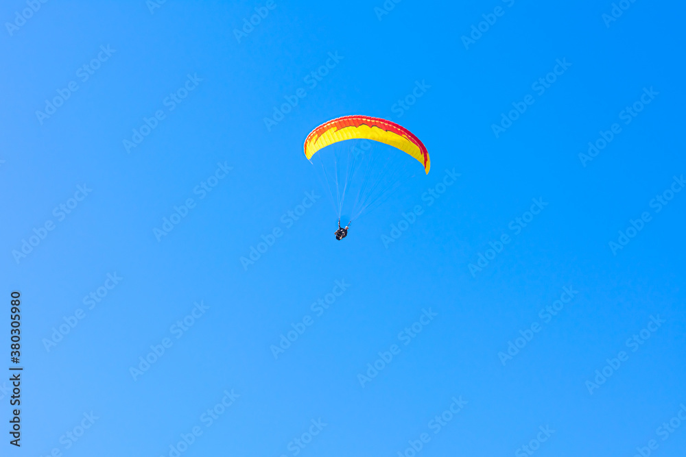Paraglider in the blue sky. The sportsman flying on a paraglider. Paraglider in the blue sky. The sportsman flying on a paraglider.