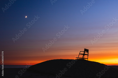 Sunset and crescent moon over a beach, with a lifeguard tower silhouette. Long Beach New York © Scott Heaney