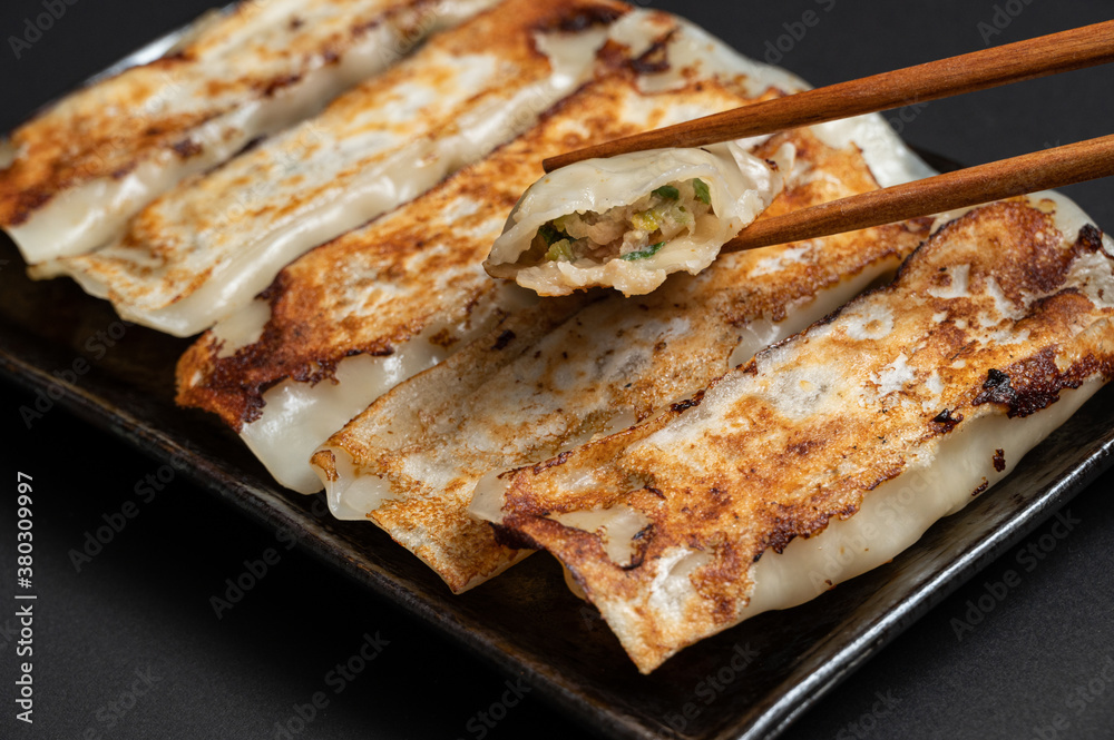 Material of traditional chinese fried dumplings(also called gyoza,pot sticker) on black background with chopsticks. Material of traditional chinese fried dumplings(also called gyoza,pot sticker) on black background with chopsticks.