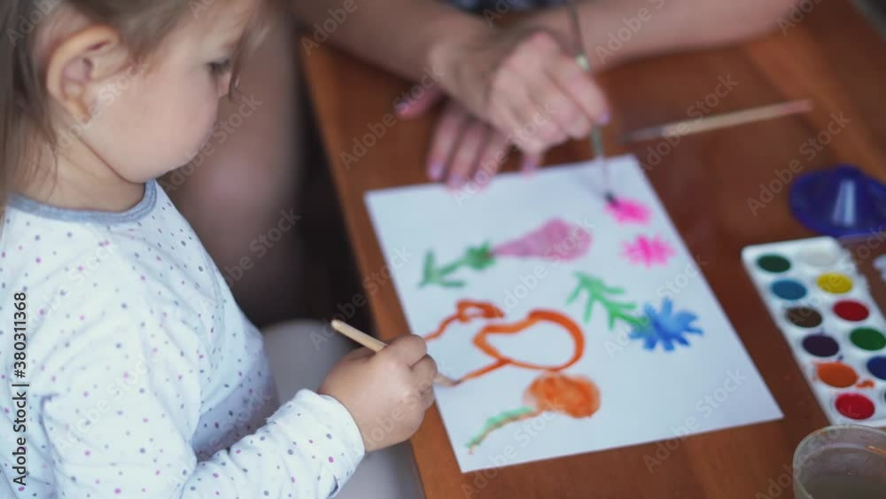 Child with granny drawing with watercolor paint at home. Simple living, connection concept Child with granny drawing with watercolor paint at home. Simple living, connection concept