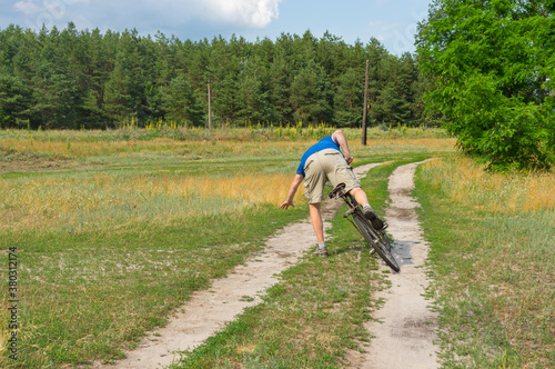 Falling off of mature man on an ancient bicycle on a country road.