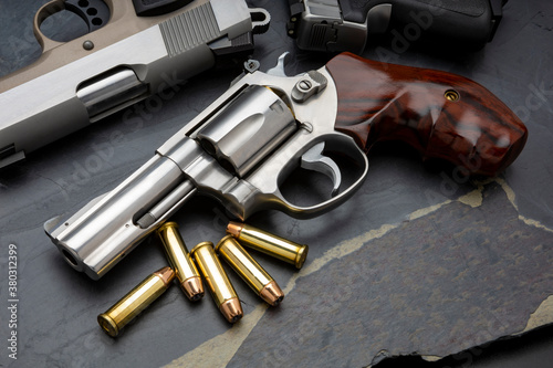 Revolver handgun and bullets on black stone background