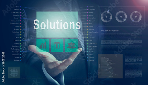 Businessman outreached hand holding a Solutions business concept on a computerised screen display.
