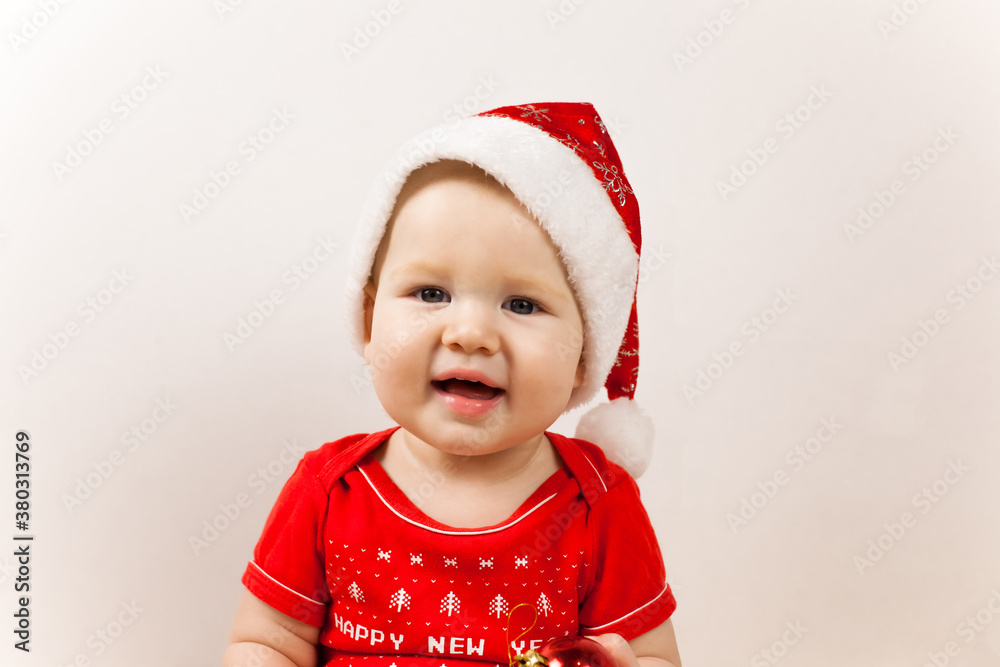 Cute little baby with Santa hat on floor and blurred Christmas lights on background Cute little baby with Santa hat on floor and blurred Christmas lights on background