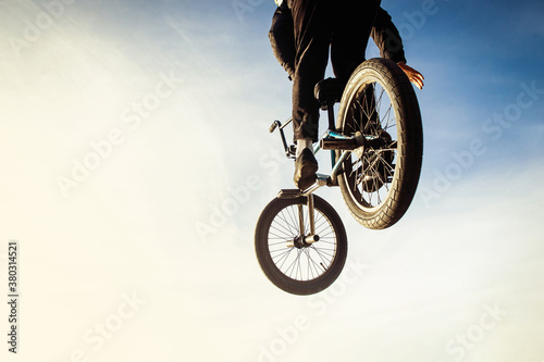 Urban biker performing acrobatic jump at sunny sky - Guy riding bmx bicycle at extreme sport competition on sunny afternoon - Alternative lifestyle concept on warm sunshine colors.