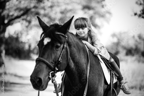 Cute little girl with long hair riding a horse outdoors. Pet therapy © sushytska
