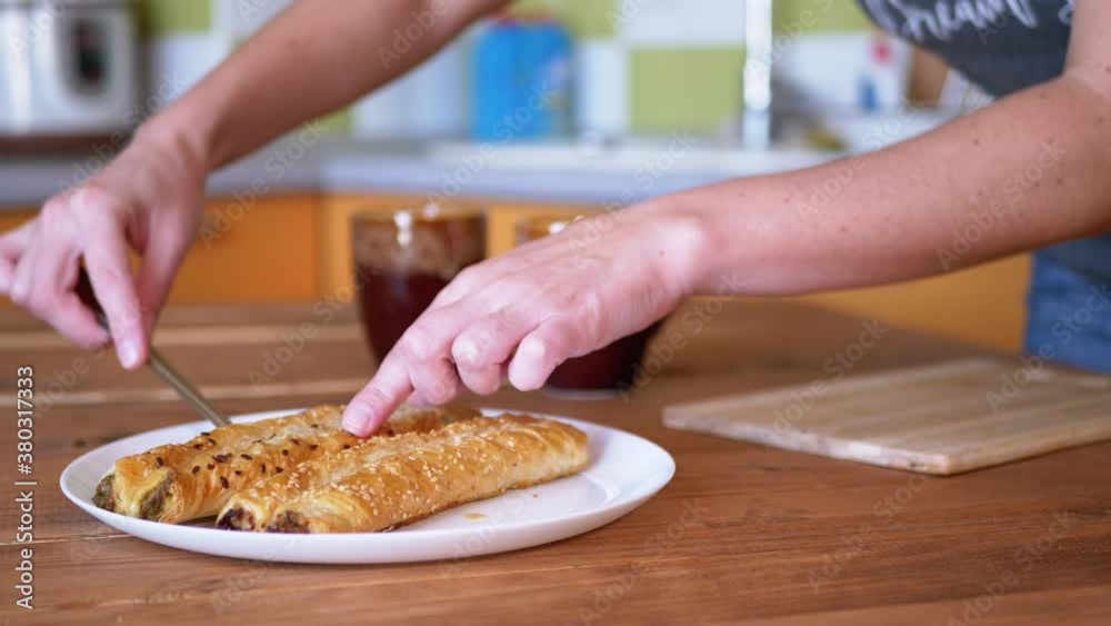 A woman puts fresh, crispy pastries from a plate onto a wooden board. Close-up.