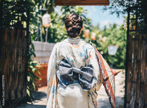 Rear view of Japanese woman wearing Yukata dress while walking in town. A Japanese yukata is a lightweight form of kimono, which is worn casually during the summer. photo