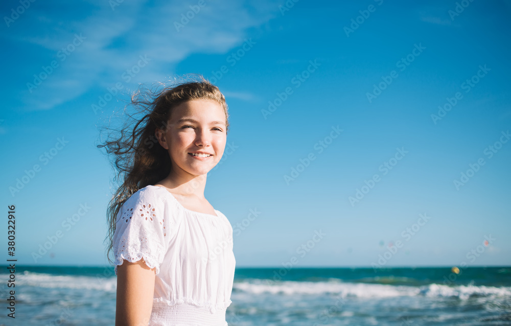 Cheerful girl standing against waving sea on sunny weather Cheerful girl standing against waving sea on sunny weather