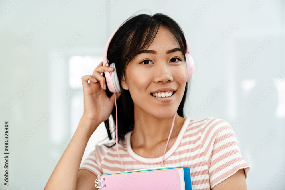 Photo of joyful asian girl smiling and posing with exercise books Photo of joyful asian girl smiling and posing with exercise books