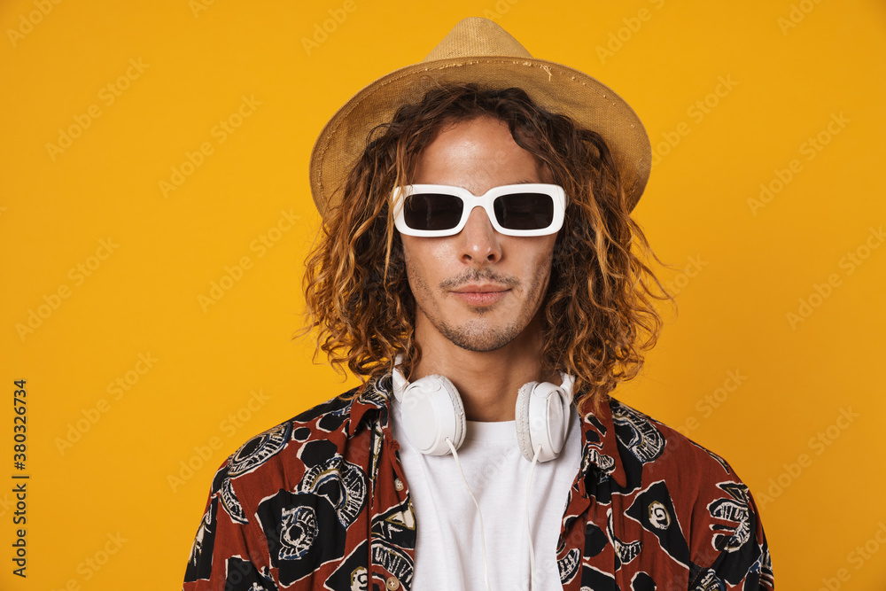 Image of handsome young man in sunglasses and hat posing at camera